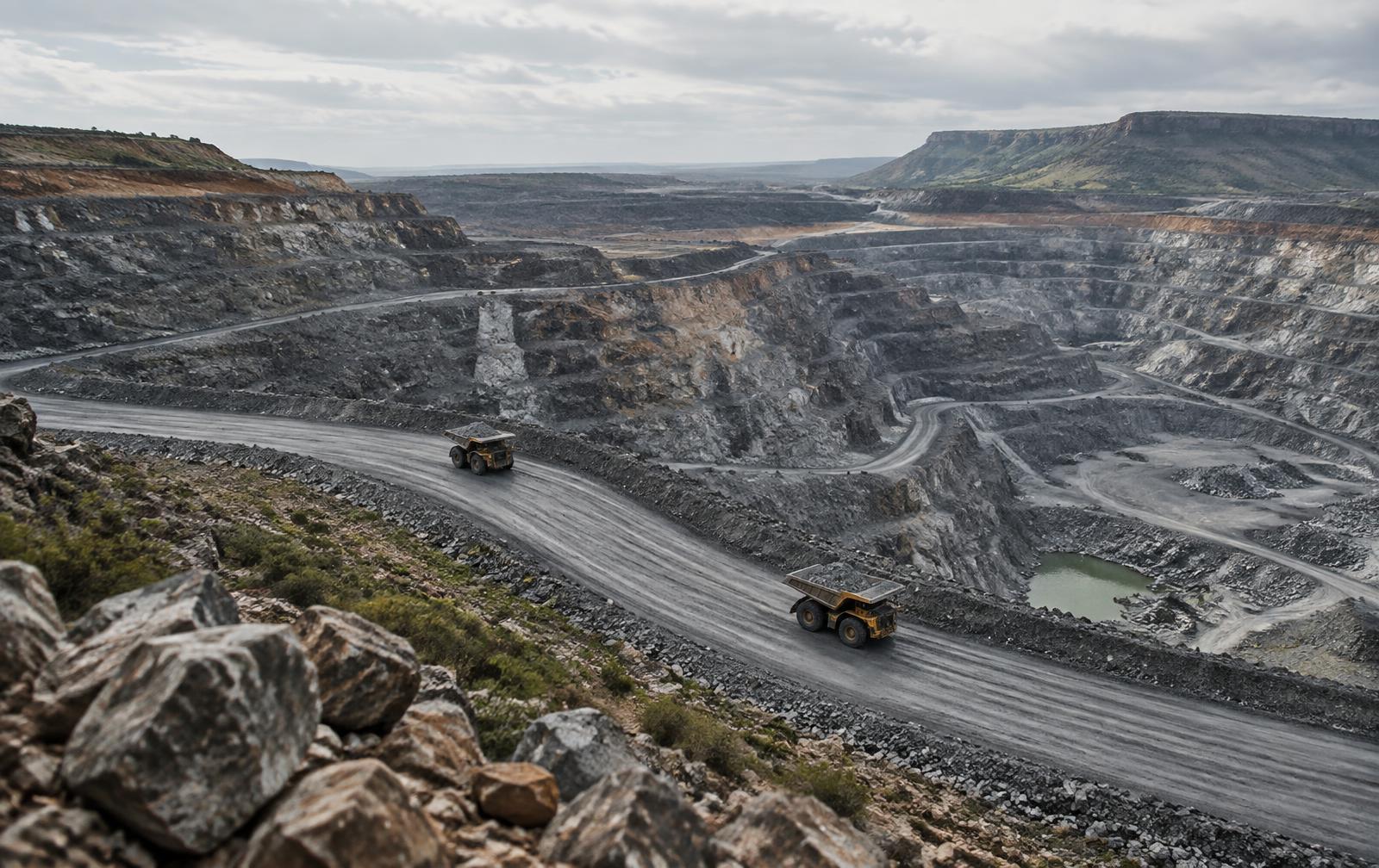 Autonomous haul trucks moving through a terraced open-pit mine